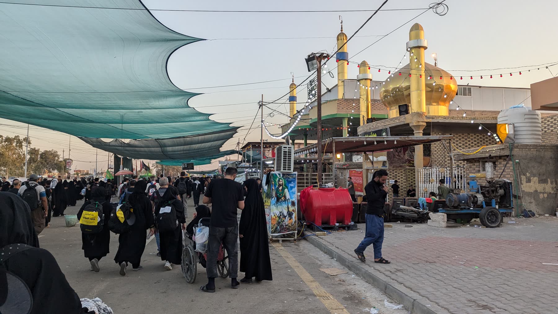 Pilgrims walking under shade netting on the Najaf to Karbala route